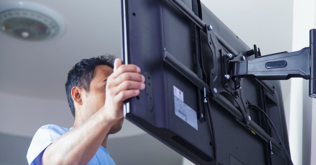 A man proudly holds up a flat screen television, showcasing its sleek design and modern features.